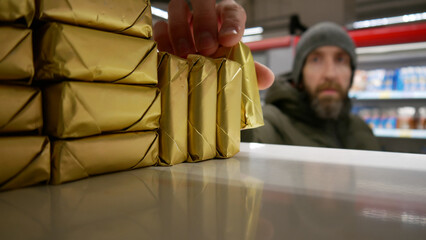 A male buyer taking a package of butter from the fridge shelf in a supermarket