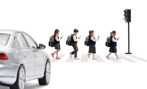 Schoolchildren With Mobile Phones Crossing A Street In Front Of A Car