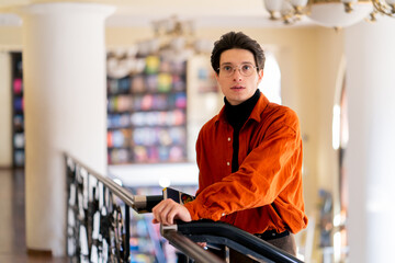 portrait of a young guy in glasses standing with a book in his hands in the library