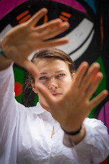 Portrait of a young woman with her face and her hands in front of a colorful painted background