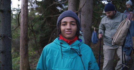 Female hiker or tourist stands in the woods, touches and looks at the tree on vacation trip or trek in autumn. Caucasian woman resting during hiking in the mountains. Outdoor recreation and travel.