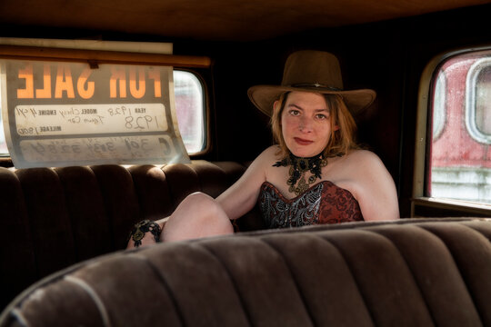 Steffi posing at the junkyard inside an old car