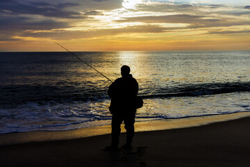 Fisherman catching fish at ocean in morning at sunrise