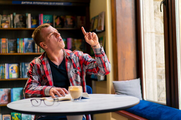 male student in the library who got an idea while reading a book against the background of...