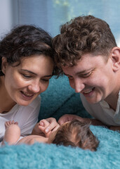 Happy family with a newborn baby. A loving mother and father gently hold their baby son in their arms and look tenderly at the child.