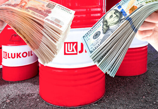 Branded Lukoil oil company barrels, russian rubles and american dollars in the hand