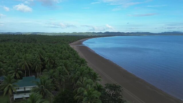 Long span of broad gently sloping strip of fine sand beach lures resort developers to put up structures &ndash; Catanauan, Quezon, Philippines. Aerial drone back tracking shot