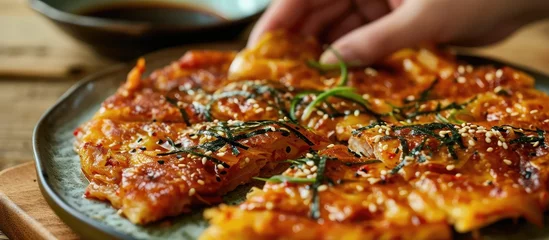 Foto op Plexiglas Eating Korean kimchi pancake with soy sauce on plate. © AkuAku