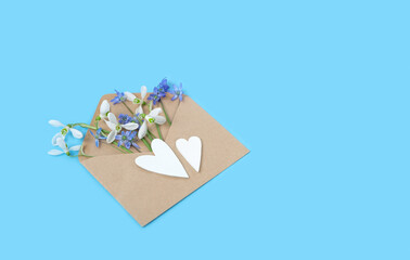 spring background. snowdrop flowers in paper envelope and decorative hearts on abstract blue backdrop. Symbol of spring season, 8 march holiday. greeting card. template for design. copy space