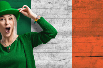 Smiling woman celebrates St. Patrick's Day. Beautiful woman in a green hat. Irish flag as background