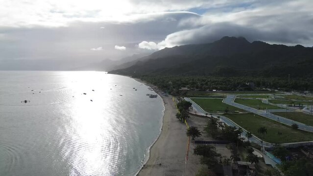 Long span of broad gently sloping strip of white fine sand beach lures resort developers to put up structures &ndash; Laiya, Batangas, Philippines. Aerial drone forward tracking shot