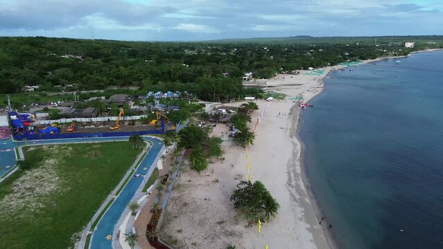 Long span of broad gently sloping strip of white fine sand beach lures resort developers to put up structures &ndash; Laiya, Batangas, Philippines. Aerial drone forward tracking shot