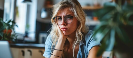 Blonde woman studying at home with a disgusted face.
