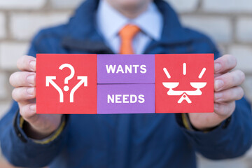 Man holding colored blocks sees text: WANTS NEEDS. Concept of Wants Needs Desires. Business,...