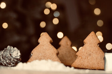 Close up of Christmas tree biscuits with out of focus lights in the background.