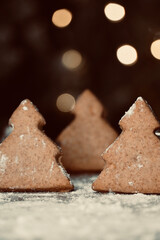 Close up of Christmas tree biscuits with out of focus lights in the background.