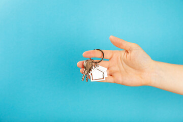 Keychain with a key ring in hand on a blue background. Concepts for real estate and moving home or...