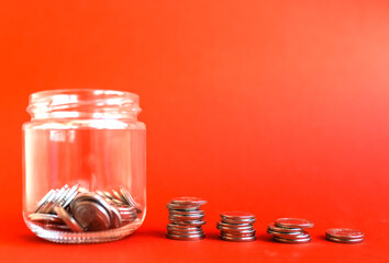 Saving money concept. Har with coins on a red background with copy space. Finansial earning or investment concept.