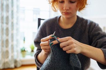 young woman knits wool product