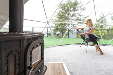 Young woman Rest in the mountains in Glamping. Cozy fireplace in a mountain house