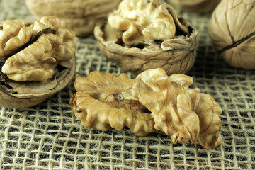 Walnuts, peeled and in shell, lie on a cloth, the nuts lie on a dark table.