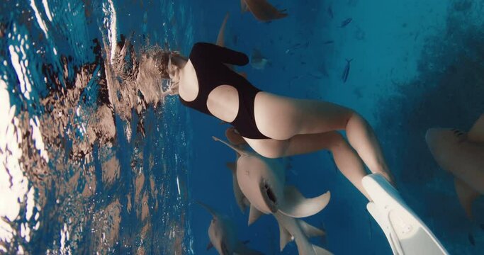 Woman freediver swimming in a clear tropical water with nurse sharks in Maldives