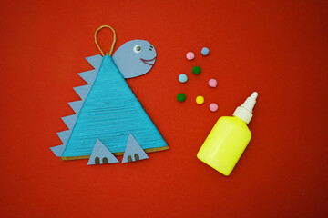 Step by step instructions how to made christmas tree toy a dinosaur of cardboard and threads lies on a red background. The The symbol of 2024. Point 6 decorate with colorful balloons.