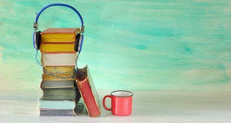 audio book concept with heap of books and vintage headphones, green background, free copy space