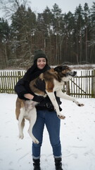 Funny friends, a girl and a dog on the background of a winter forest