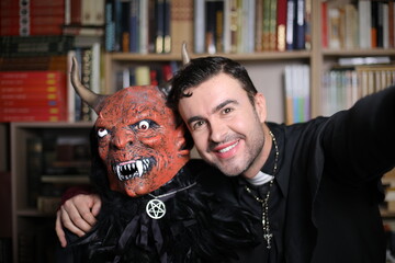 Man and friend dressed as demon and priest for Halloween taking a selfie