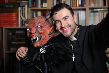 Man and friend dressed as demon and priest for Halloween taking a selfie