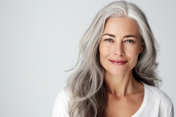 Naklejka premium Beautiful senior woman with smooth healthy face skin and grey long hair. Gorgeous aging mature woman happy smiling on white background. Beauty and cosmetics skincare advertising concept