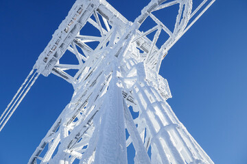 Tramway tower  covered in frost against a deep blue cloudless sky, tram cables are also frost covered, on a very cold January morning in NH, view is from bottom of tower looking straight up