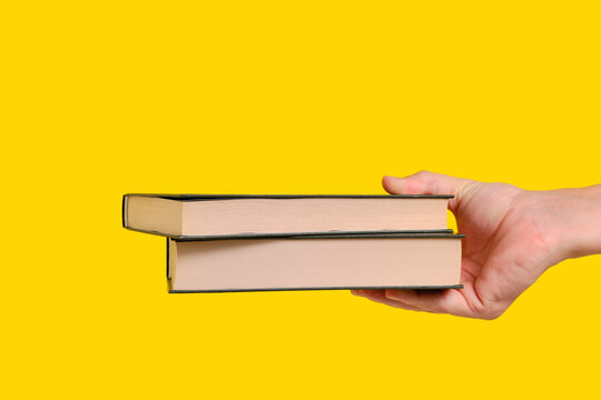 Books in hand yellow background. International book giving day.
