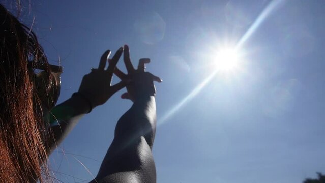 Happiness of freedom in a beach at noon. Sunlight between fingers. Silhouette of happy girl in beach
