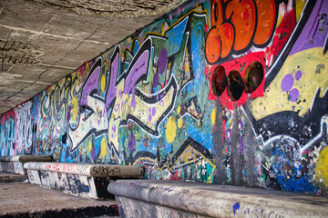 Colorful graffiti spray-painted on an urban wall in an underpass tunnel at daytime