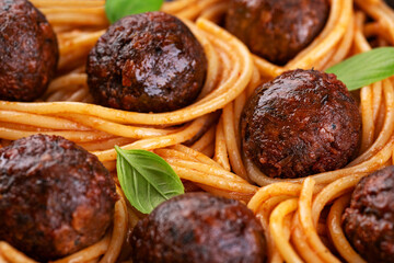 Fried vegan meatballs with noodles and basil leaves.
