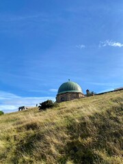 Observatory on the hill with green grass field on a sunny and windy day.