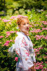 Portrait of a young woman wearing a Japanese yukata summer kimono in a hydrangea garden. Kyoto,...