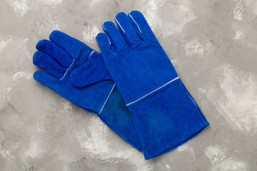 Blue construction gloves on concrete background, top view