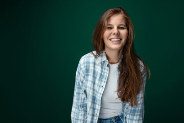 Charming smiling Caucasian young woman having fun on green studio background