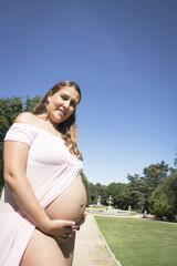 Seven month pregnant woman standing dressed in pink