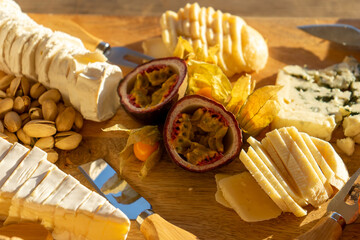 Assortment of cheeses on a wooden board with passion fruit and pistachios. Gourmet delicacies for...
