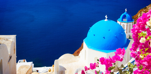 traditional blue dome of church and blue sea water, Oia, Santorini with flowers