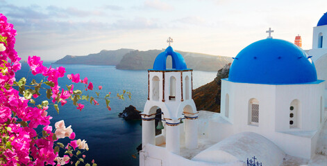 traditional greek village Oia of Santorini, with blue domes of churches in sunset light with...