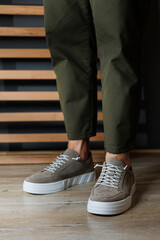 Collection of men's summer shoes. Male legs in beige leather sneakers. Men's classic shoes.