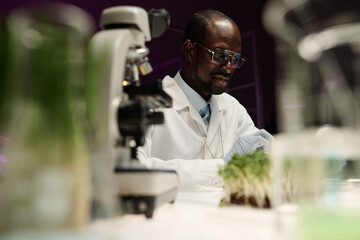 Low angle shot of african american scientist sitting at his table in laboratory