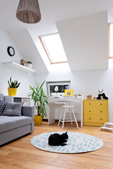 Child room in modern design in the attic with window. Desk with chair and sofa with yellow decor in...