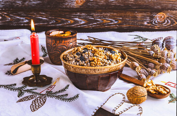 Ukrainian Christmas dish kutia, wheat porridge with nuts, poppy seeds, raisins. A candle and ears of wheat as a decoration
