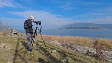 A man birdwatching with a telescope on Lake Egirdir in Turkey. - obrazy, fototapety, plakaty